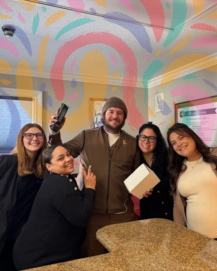 Dental team members celebrating their delivery driver at the front desk in Lunenburg